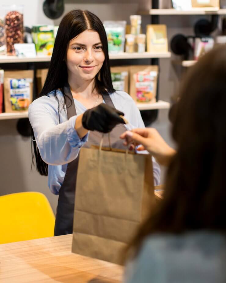front-view-sales-assistant-handing-out-groceries-bag